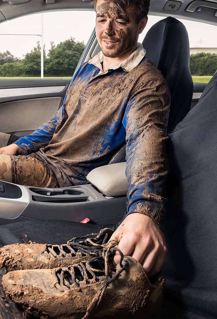 Man covered in mud sitting on heavy duty car seat cover
