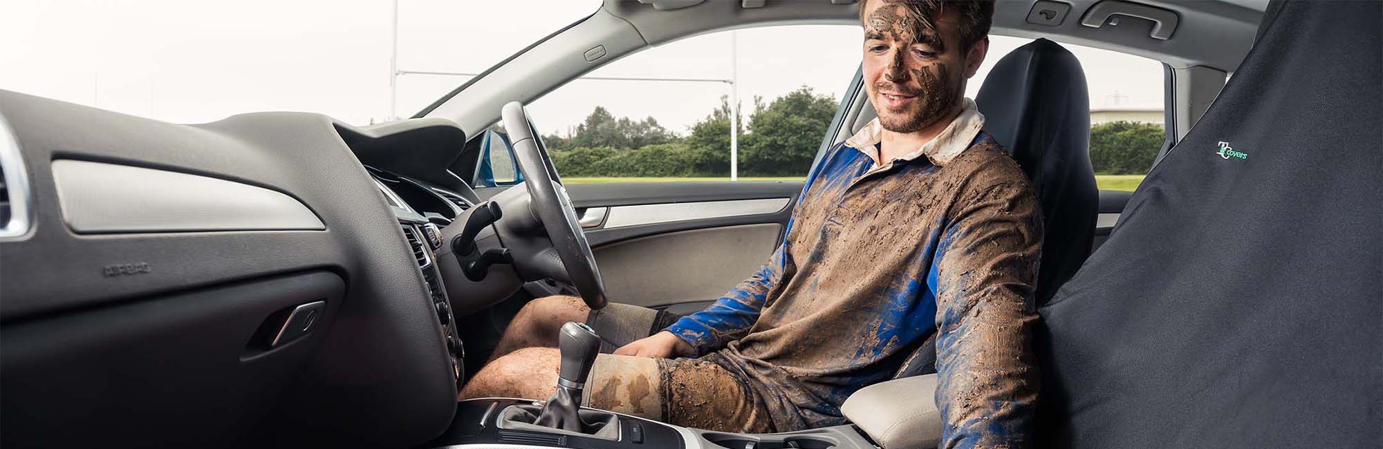 Man covered in mud sitting on heavy duty car seat cover