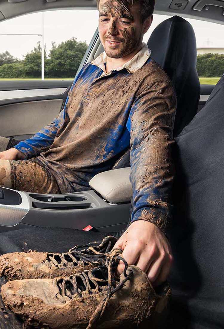 A man covered in dirt sitting on universal auto seat covers